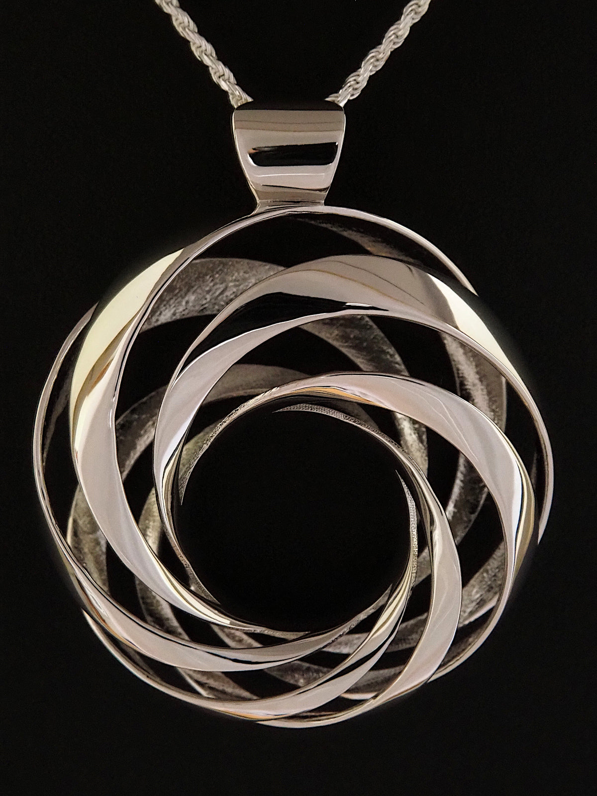 Close-up of a 35mm rhodium-plated brass cyclide pendant on a silver French rope chain.