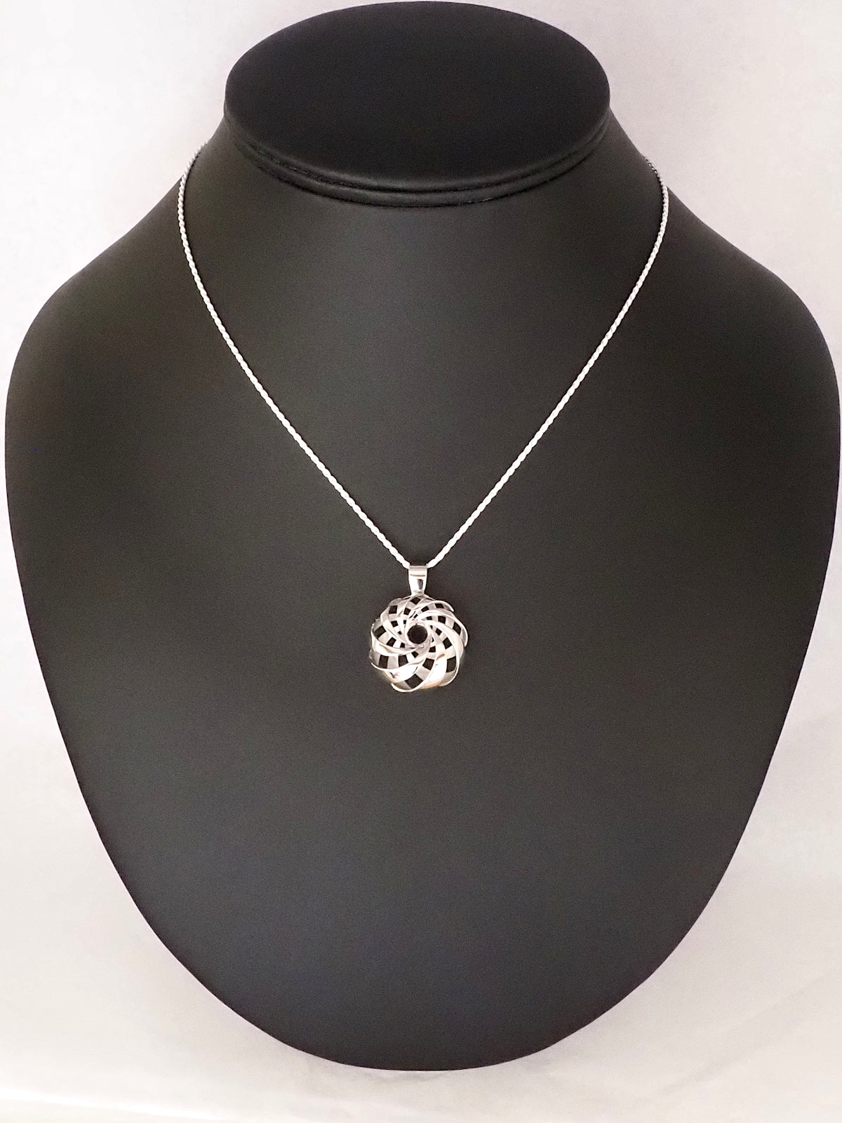 A 25mm rhodium-plated brass cyclide pendant with a silver French rope chain on a necklace display.