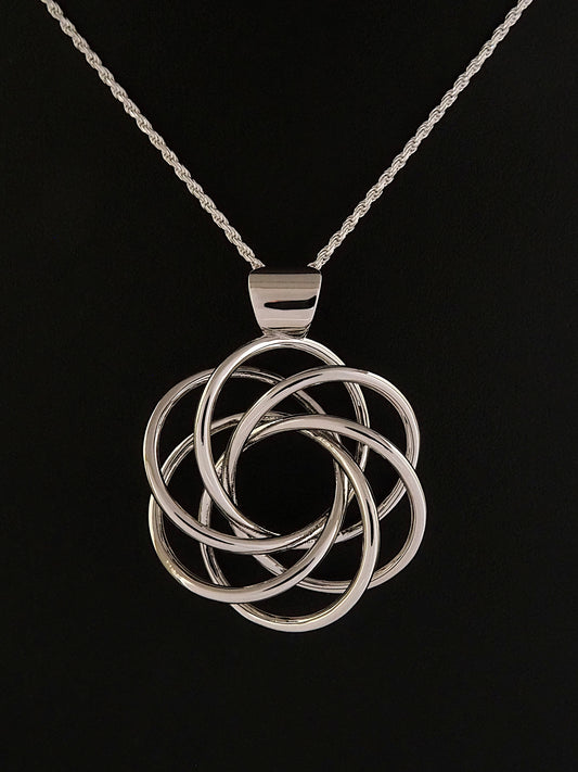 Photograph of a rhodium-plated flower-like Harmonia pendant with six-fold symmetry on a black background