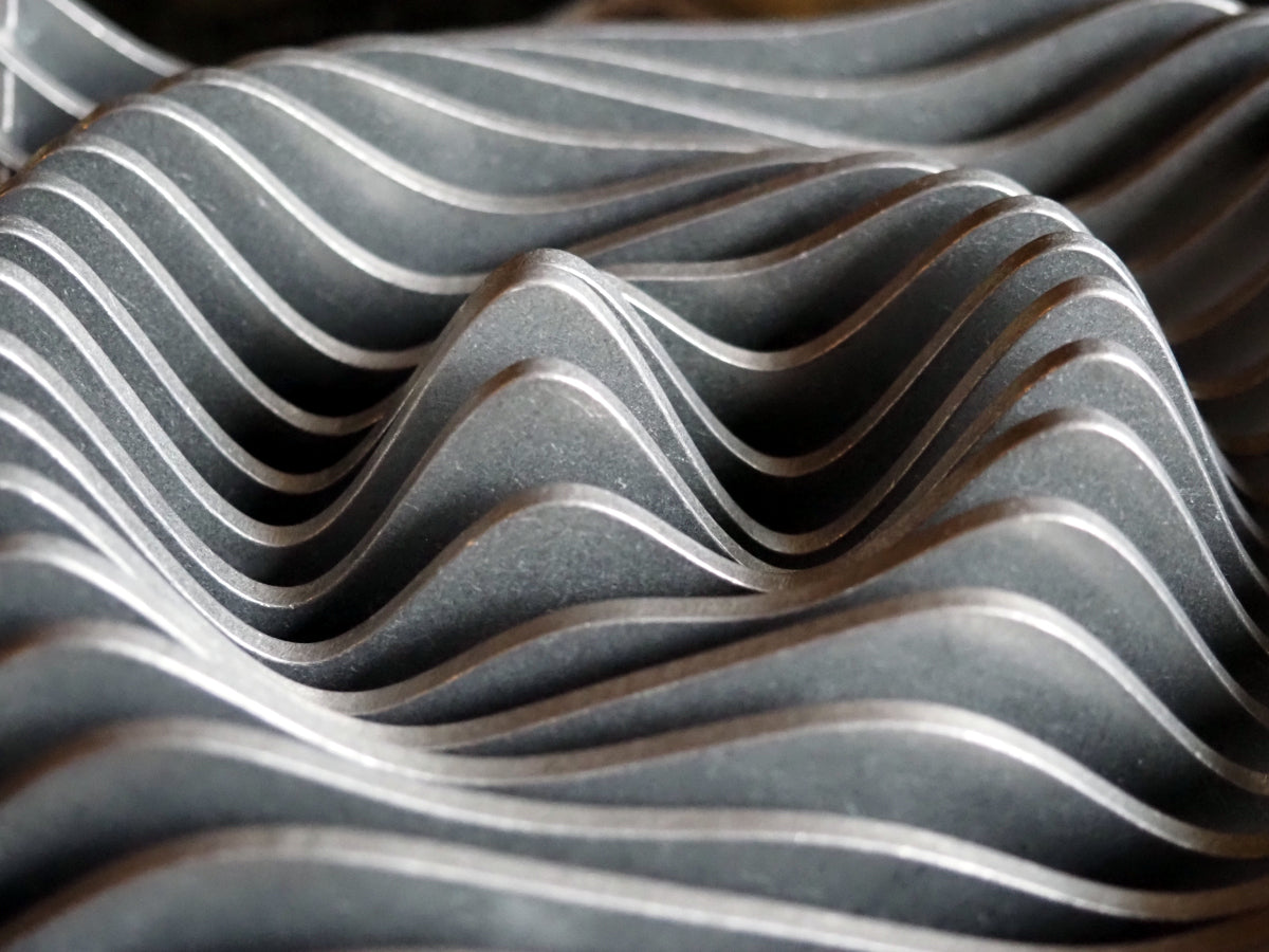 Photograph of layered sinusoidal curves cut from sheet metal