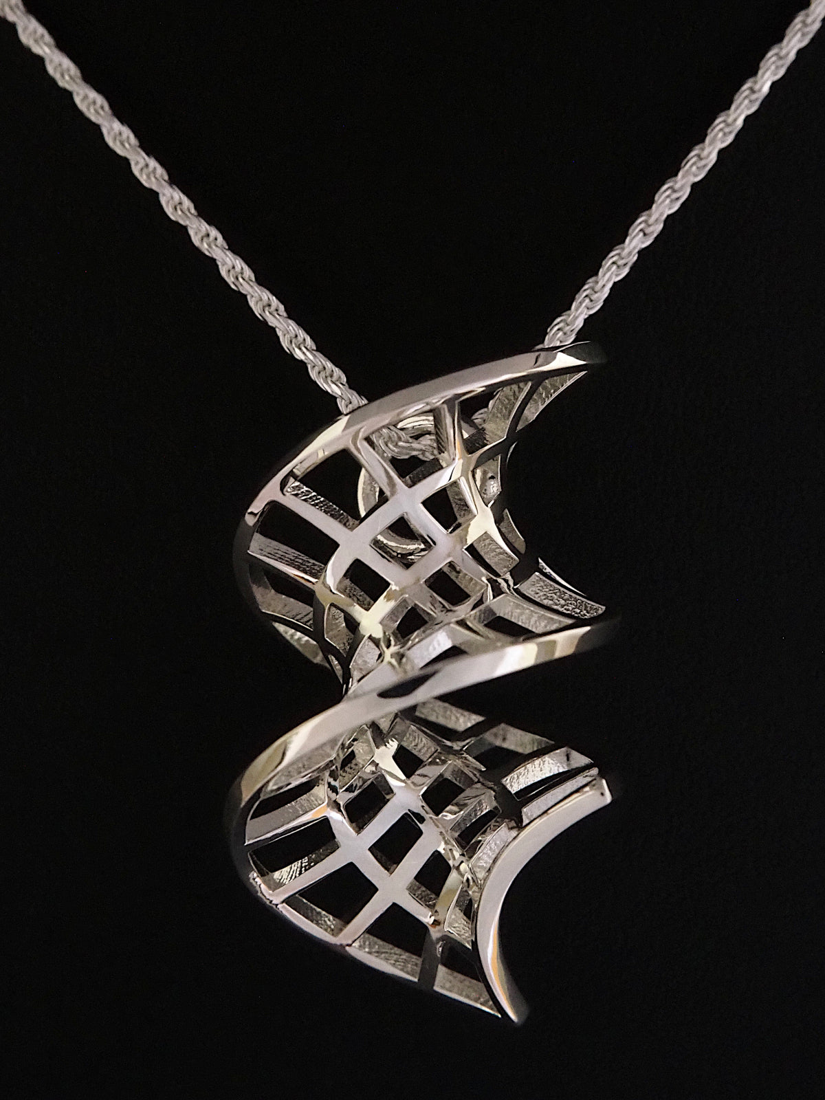 Close-up of a silver catenoid-helicoid pendant on a silver French rope chain.